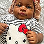 Clover is registered to the contest to win money with this photo: baby, infant, child, face, bonnet, clothing, striped_shirt, hello_kitty, hand, skin, portrait, lying_down, bedspread, floral_pattern, cute, closeup, looking_at_camera, indoors, adorable, young_child