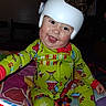 Frankie is registered to the contest to win money with this photo: baby, child, smiling, helmet, pajamas, christmas_theme, toy_car, blanket, indoor, happy, cute, face, person, infant, holiday, colorful, sitting, playful, young_child, cozy