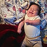baby, smiling, blanket, bed, clothing, happy, infant, person, sleepwear, cute, face, skin, head, lying_down, toddler, indoor, comfort, soft, warm, child