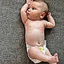 baby, infant, diaper, couch, gray, skin, arm, leg, face, head, foot, hand, lying_down, texture, curious, child, indoors, person, newborn, expression