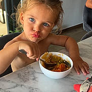 Naim participe au concours pour gagner de l'argent avec cette photo : child, toddler, blue_eyes, messy_hair, eating, bowl, food, spoon, marble_table, indoor, pouty_face, messy, person, cute, meal_time, table, hand, skin, expression, casual