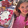 child, girl, birthday_cake, pink_dress, party, macarons, cake, smile, celebration, frosting, table, food, outdoor, happy, person, dessert, crown, hand, sunlight, festive