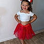 Lila a rejoint le concours — aidez-le/la à gagner de superbes lots ! child, girl, smile, tutu, red_skirt, white_top, bow, headband, sandals, floor, wooden_floor, standing, posing, indoor, wall, door, happy, cute, fashion, portrait