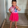 child, girl, pink_tutu, pink_shoes, smiling, bracelet, wooden_floor, home_interior, rug, cabinet, mirror, vase, flowers, door, happy, standing, posing, cute, indoor, casual_clothing