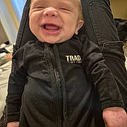 Riley joined the competition — help win amazing prizes! baby, child, laughing, black_clothing, indoor, person, legs, smiling, infant, happy, young_child, casual, portrait, closeup, human, fingers, face, cute, sitting, zipper