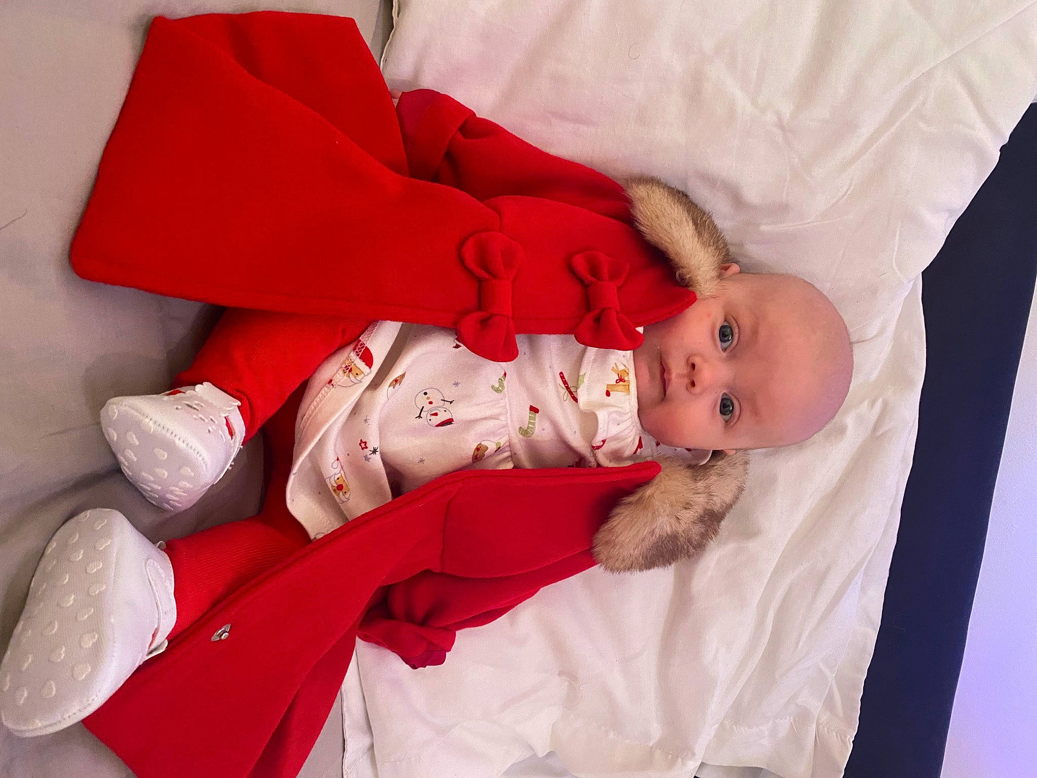 Maisie is registered to the contest to win money with this photo: baby, baby_products, baby_toddler_clothing, carmine, child, comfort, dress, event, foot, hat, human_body, human_leg, lap, leg, person, room, sitting, skin, sleeve, sock
