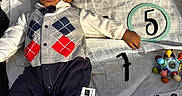 Amor joined the competition — help win amazing prizes! argyle_vest, baby, blanket, bow_tie, child, clothing, cute, face, five_months, footwear, hand, indoors, infant, lying_down, milestone_blanket, numbers, patterned_clothing, ring, smiling, toy