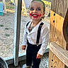 black_pants, child, daylight, face_paint, green_hair, happy, joker_costume, outdoor, person, playful, porch, red_lipstick, smiling, socks, suspenders, tattoos, toddler, white_shirt, window_screen, wooden_floor