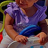 toddler, child, smiling, curly_hair, purple_shirt, toy, ride_on_car, steering_wheel, outdoor, sunlight, happy, play, cute, baby, person, sitting, daylight, hands, face, portrait