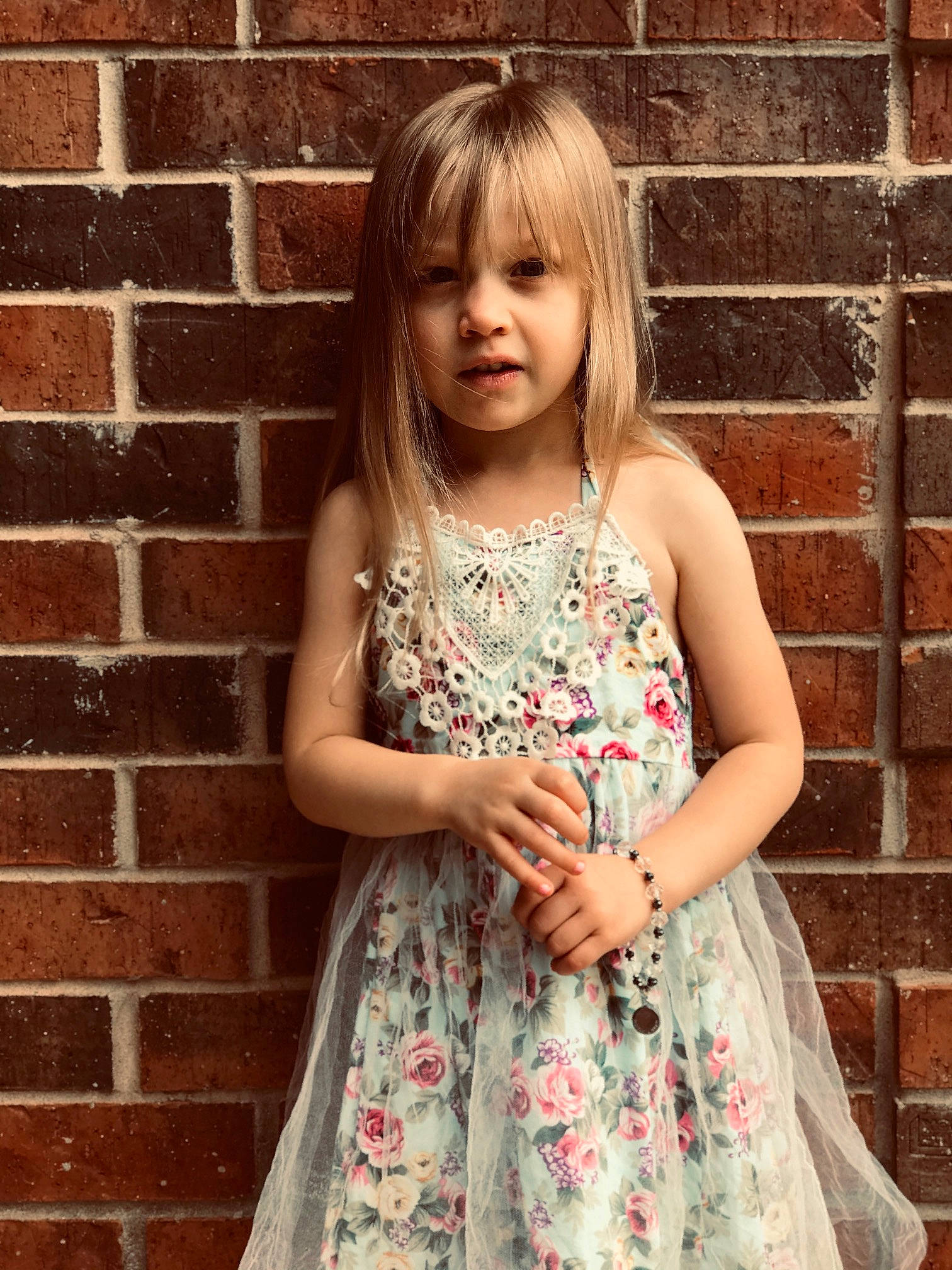 Nola is registered to the contest to win money with this photo: bangs, beauty, beige, blond, brown_hair, child, child_model, clothing, dress, hair, hairstyle, long_hair, pattern, person, photo_shoot, photography, plant, smile, textile, toddler