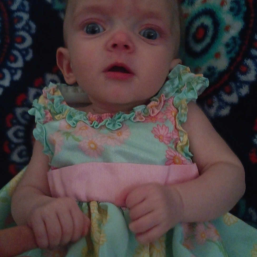 Laynna joined the competition — help win amazing prizes! baby, child, clothing, colorful, cute, dress, expression, finger, floral_pattern, hand, human, indoor, infant, looking, patterned_background, person, portrait, skin, small_hands, wide_eyes