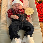 August joined the competition — help win amazing prizes! baby, infant, sleeping, santa_hat, plaid_shirt, suspenders, denim_pants, white_booties, wooden_sign, christmas_tree, holiday, festive, cushioned_chair, carpet, indoors, peaceful, cute, child, holiday_decor, seasonal