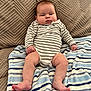 August is registered to the contest to win money with this photo: baby, infant, striped_onesie, blanket, couch, furniture, indoors, person, legs, feet, face, expression, skin, hand, sitting, comfort, texture, head, casual, resting
