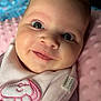 baby, smiling, face, close_up, blanket, pink, soft_texture, cute, infant, portrait, child, sleepwear, cozy, indoors, eyelashes, expression, head, clothing, fabric, young
