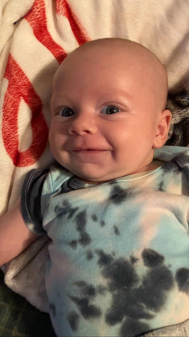 August is registered to the contest to win money with this photo: baby, baby_toddler_clothing, cheek, child, chin, comfort, eye, eyebrow, facial_expression, happy, iris, linens, lip, mouth, nose, person, pink, skin, sleeve, smile