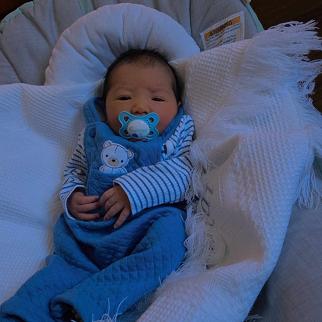Malakai is registered to the contest to win money with this photo: baby, baby_bouncer, blanket, blue_clothing, comfort, cozy, cushion, cute, face, fringe, hands, indoor, infant, newborn, pacifier, plush, portrait, resting, striped_shirt, wooden_floor