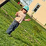 Rae is registered to the contest to win money with this photo: child, helmet, grass, dandelions, bubbles, house, outdoor, playing, curious, casual_clothing, sunny_day, greenery, tree, window, pants, footwear, person, nature, garden, summer