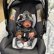 Levy is registered to the contest to win money with this photo: baby, infant, car_seat, onesie, sleeping, blanket, hospital, medical_equipment, newborn, clothing, soft_toys, cute, person, bed, fabric, headwear, indoors, resting, child, seatbelt