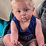 baby, blonde_hair, blue_tank_top, casual_clothing, child, couch, curious, cushion, expression, face, foot, hand, indoors, infant, person, portrait, shorts, sitting, skin, toes