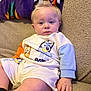 baby, blanket, blue_eyes, cartoon_clothing, child, colorful, couch, cute, hand, indoor, infant, light_hair, long_sleeve, portrait, relaxed, seated, shorts, soft_light, texture, young