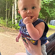Kingston is registered to the contest to win money with this photo: baby, child, hand, fingers, person, outdoor, forest, trees, greenery, clothing, shorts, sleeveless_shirt, skin, face, eyes, hair, holding, nature, summer, curious