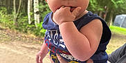 Kingston is registered to the contest to win money with this photo: baby, child, hand, fingers, person, outdoor, forest, trees, greenery, clothing, shorts, sleeveless_shirt, skin, face, eyes, hair, holding, nature, summer, curious