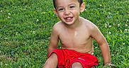 Ray is registered to the contest to win money with this photo: child, toddler, smiling, barefoot, red_shorts, grass, outdoor, sunlight, happy, young, boy, casual, nature, summer, playful, cute, portrait, sitting, greenery, daytime