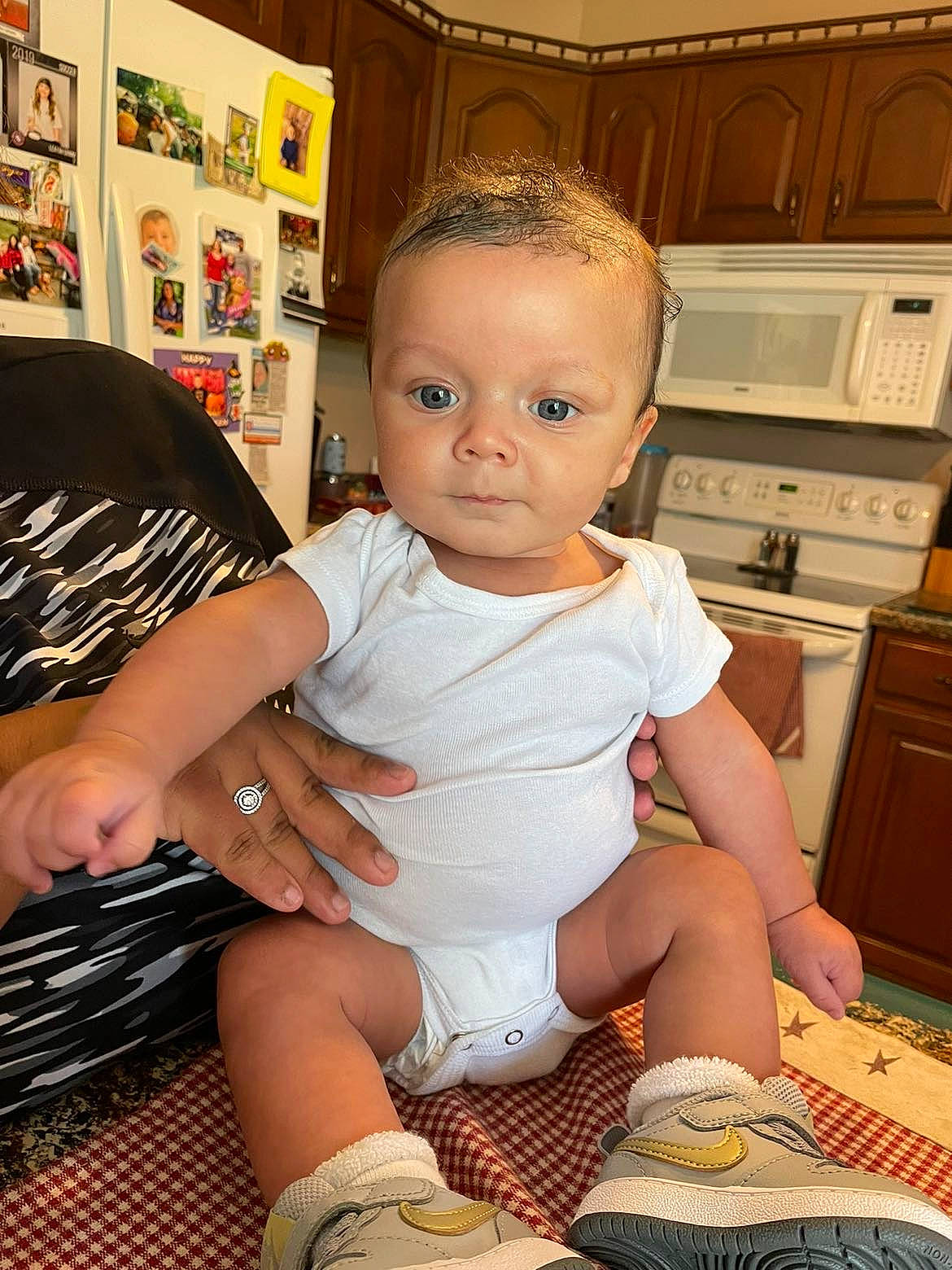 Darion is registered to the contest to win money with this photo: baby, baby_toddler_clothing, cabinetry, child, countertop, drawer, flooring, gas_stove, home_appliance, human_leg, kitchen_appliance, kitchen_stove, knee, leg, person, room, sandal, shoe, sock, thigh