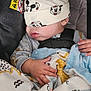 baby, sleeping, car_seat, mickey_mouse, hat, blanket, dinosaur_pattern, hand, clothing, child, infant, cute, resting, seatbelt, fabric, soft, indoors, warning_label, comfort, peaceful