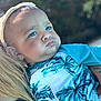 baby, child, face, blue_eyes, headband, leaf_pattern, clothing, person, outdoor, nature, portrait, expression, holding, blonde_hair, skin, cute, serious, young_child, close_up, sunlight