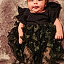baby, bodypart, clothing, costume, couch, dress, face, finger, furniture, hand, happy, head, newborn, pants, person, photography, portrait, sitting, skirt, smile