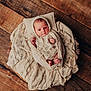 Luna is registered to the contest to win money with this photo: baby, infant, newborn, basket, blanket, knitwear, wooden_floor, cozy, wrapped, cute, small, face, headwear, hands, feet, soft, texture, indoors, portrait, sleeping_area