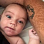 baby, infant, face, arm, tattoo, skin, closeup, portrait, person, expression, eyes, hand, lying_down, resting, cute, child, indoor, human, head, protection