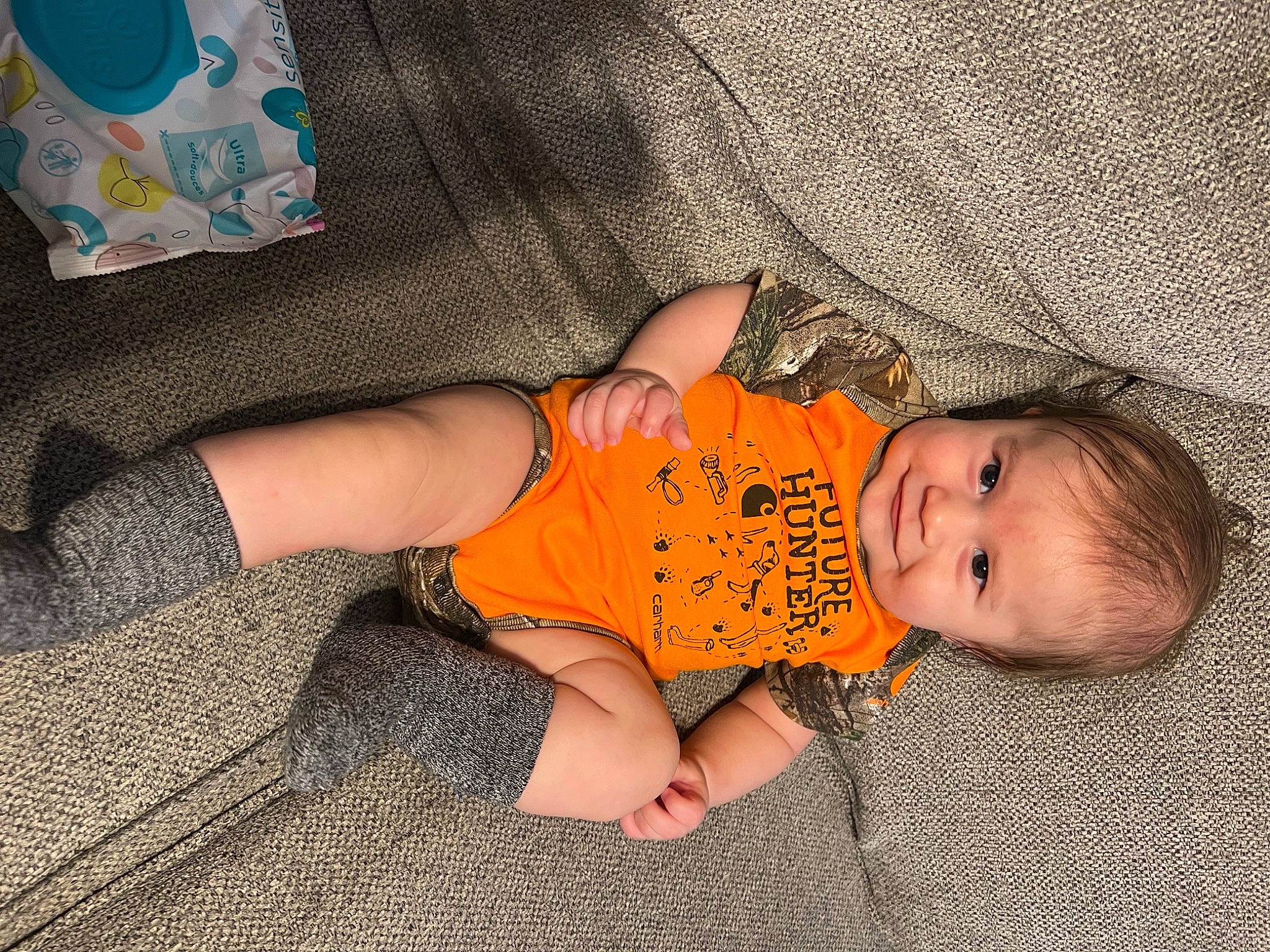 Waylynn is registered to the contest to win money with this photo: baby, baby_toddler_clothing, comfort, finger, floor, flooring, grass, hand, head, joy, leg, nail, orange, pattern, person, skin, sleeve, smile, textile, thigh