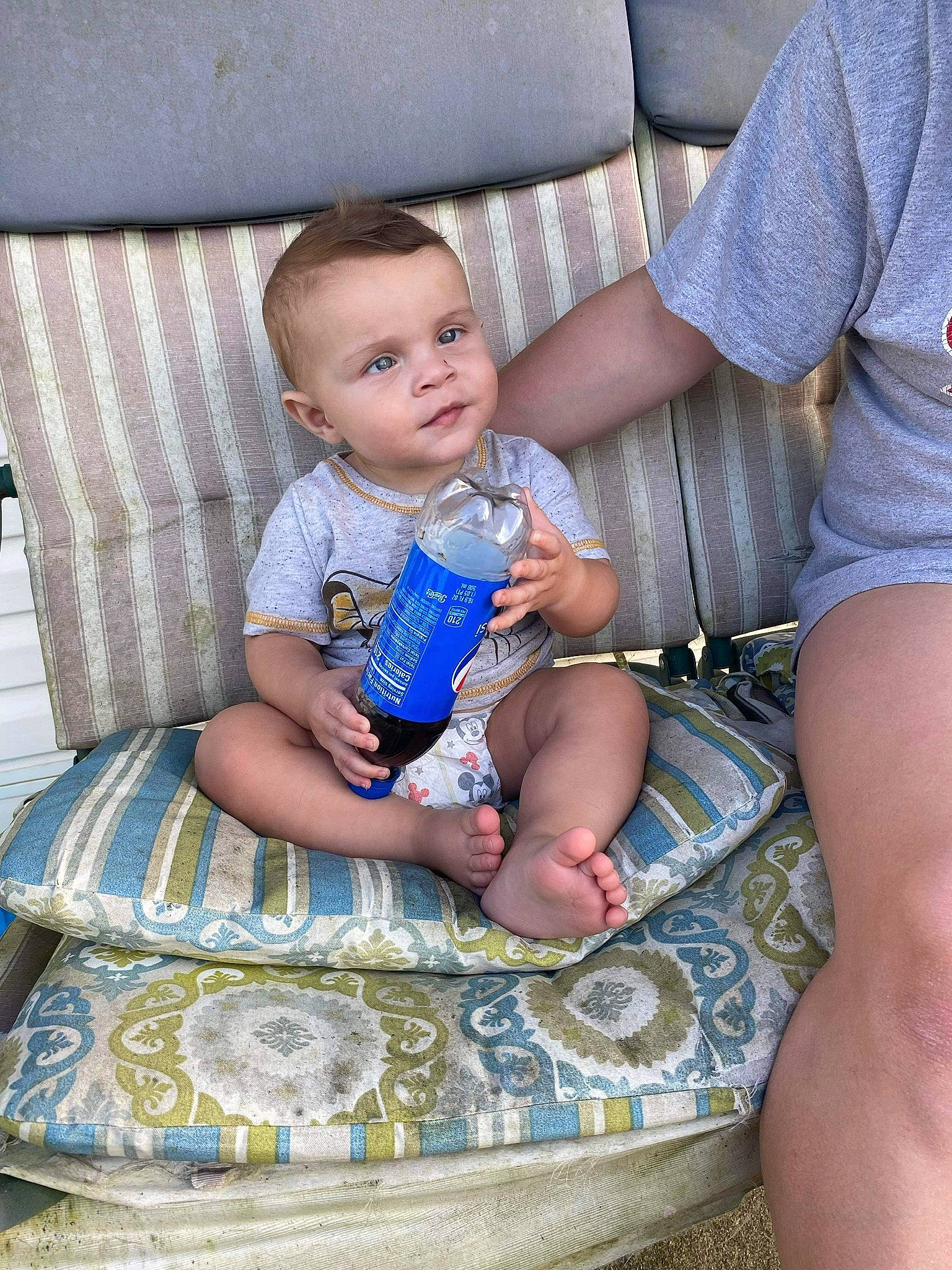 Greyson is registered to the contest to win money with this photo: arm, baby, bottle, child, comfort, drinkware, electric_blue, fun, hairstyle, hand, human, human_leg, lap, leg, mouth, person, plastic_bottle, sitting, thigh, toddler