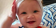 Leila joined the competition — help win amazing prizes! apparel, baby, blanket, blue, child, clothing, cute, face, hand, happy, headband, indoors, infant, pattern, person, portrait, red, smile, toddler, white