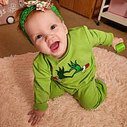 Leila joined the competition — help win amazing prizes! baby, child, smiling, crawling, green_clothing, headband, indoor, rug, toy, carpet, person, happy, cute, floor, home, furniture, playful, infant, childhood, bright_colors