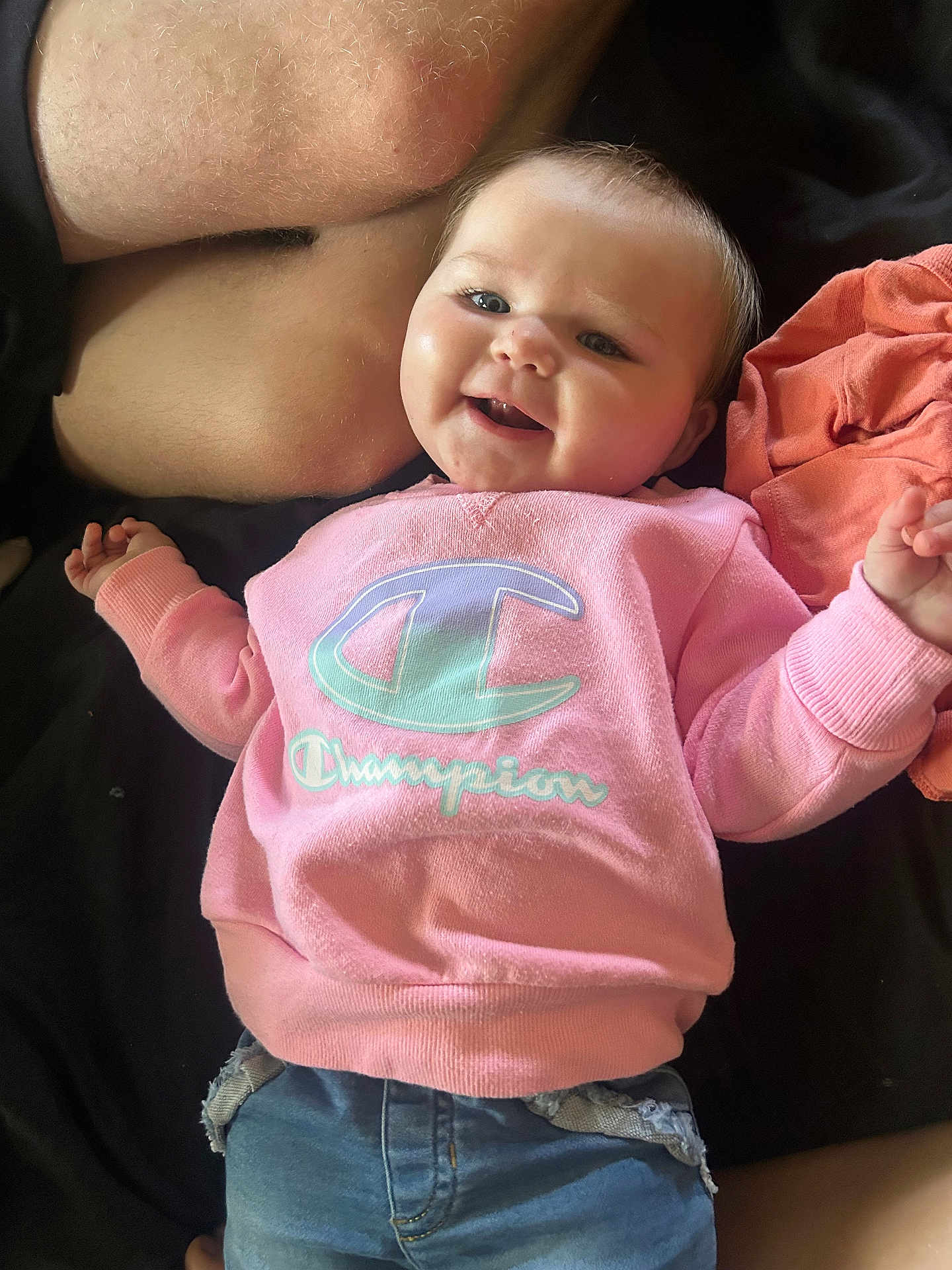 Paisley is registered to the contest to win money with this photo: baby, child, smiling, pink_sweatshirt, champion_logo, jeans, person, portrait, happy, casual_clothing, indoor, cute, infant, human, apparel, sitting, face, skin, hand, young