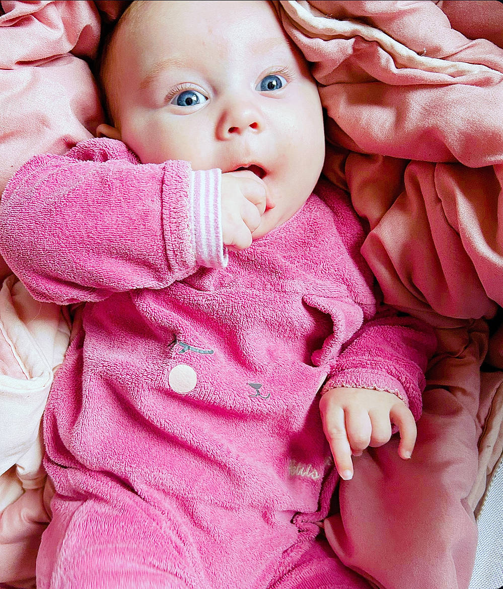 Léna participe au concours pour gagner de l'argent avec cette photo : baby, baby_toddler_clothing, cheek, chin, comfort, eye, face, facial_expression, hand, head, lip, mouth, nose, organ, outerwear, person, pink, skin, sleeve, textile