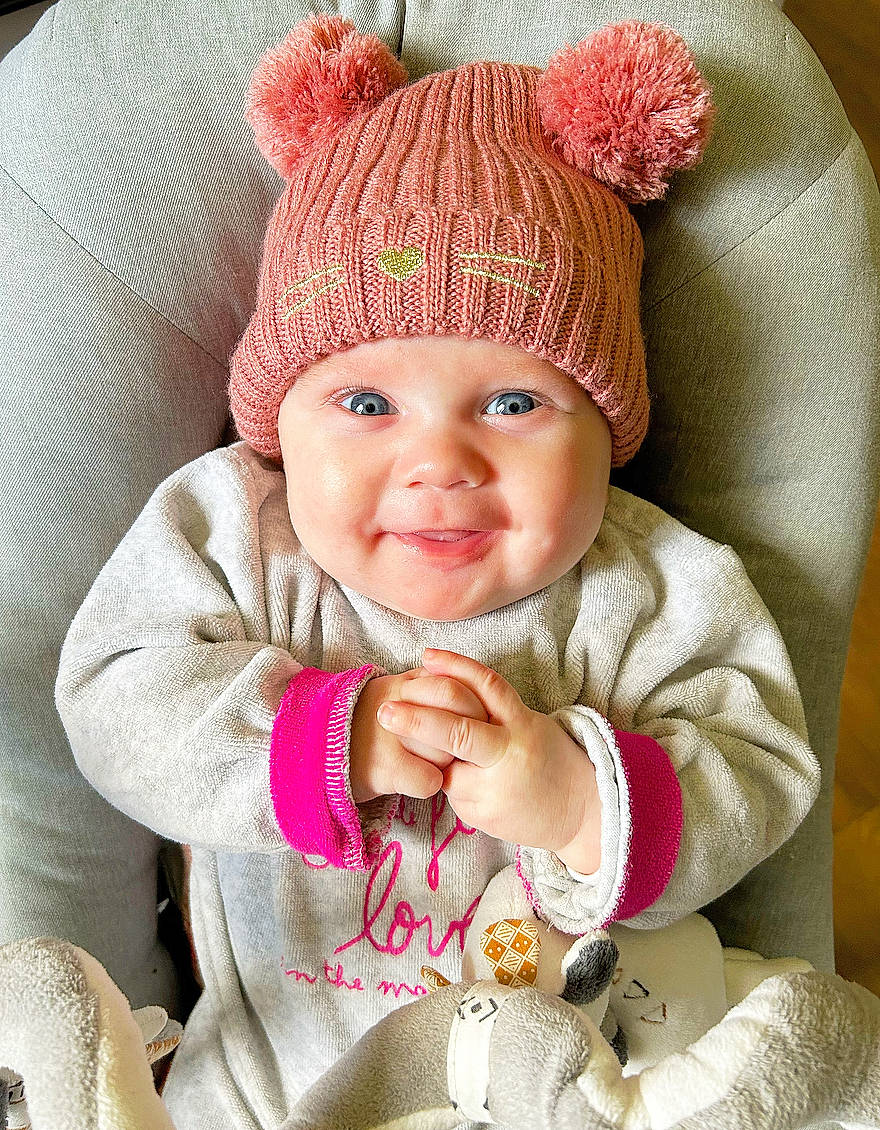 Léna a rejoint le concours — aidez-le/la à gagner de superbes lots ! baby, baby_toddler_clothing, cap, cheek, eye, happy, head, headgear, headwear, jacket, knit_cap, lip, outerwear, person, pink, product, sleeve, smile, textile, toddler