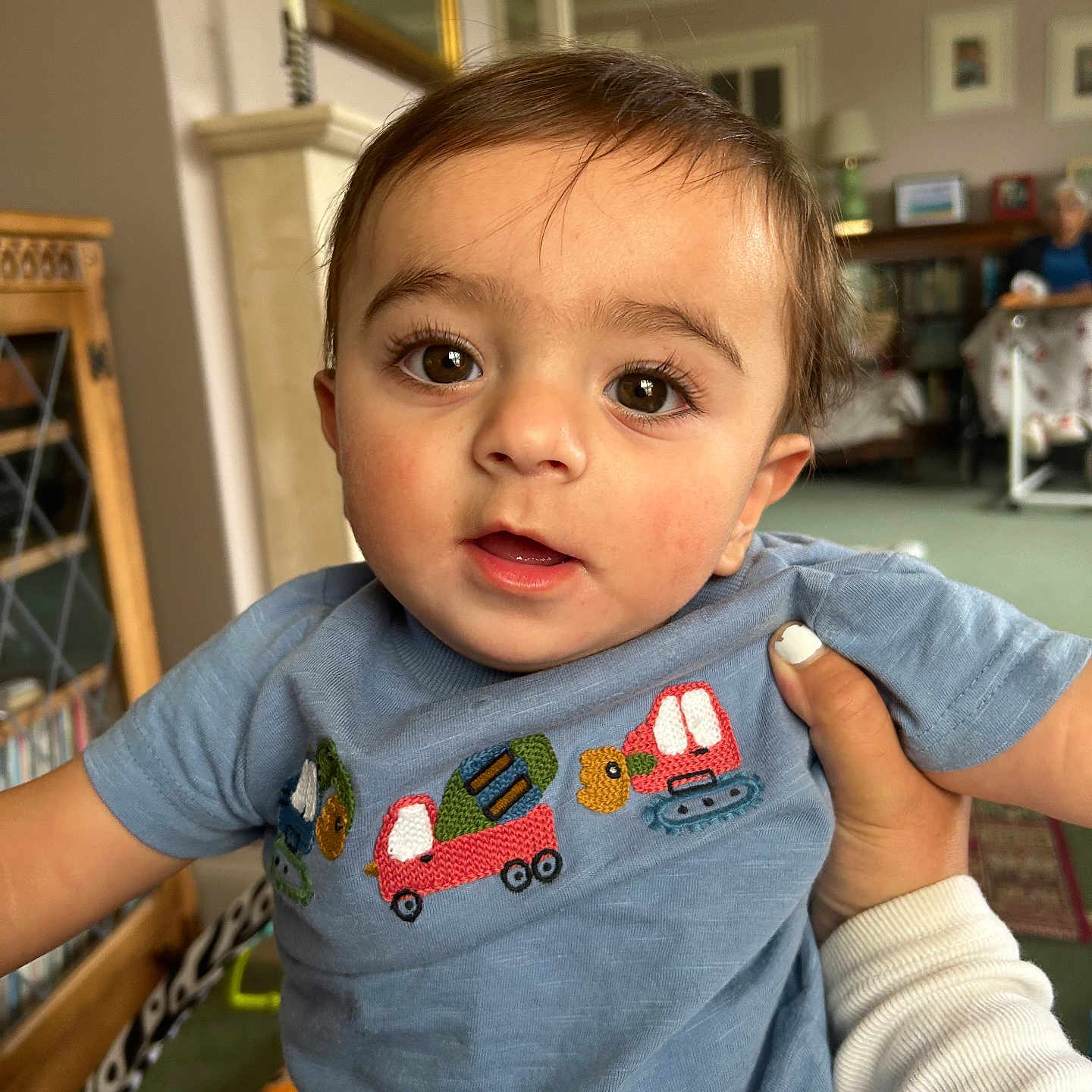 Kyh is registered to the contest to win money with this photo: blue_shirt, bookshelf, carpet, child, closeup, cozy, curious, elderly_person, embroidery, eyes, face, furniture, hand, indoors, living_room, mirror, nail_polish, person, portrait, toddler