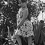 Kaitlyn is registered to the contest to win money with this photo: child, girl, posing, dress, headband, garden, plants, leaves, outdoor, sunlight, flip_flops, flower_bed, fence, shrubbery, nature, standing, playful, summer, casual, portrait