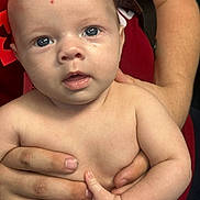 Carter joined the competition — help win amazing prizes! baby, infant, child, skin, face, eyes, hand, adult_hand, holding, red_shirt, portrait, close_up, expression, curious, human, fingernails, forehead, person, skin_tone, indoor