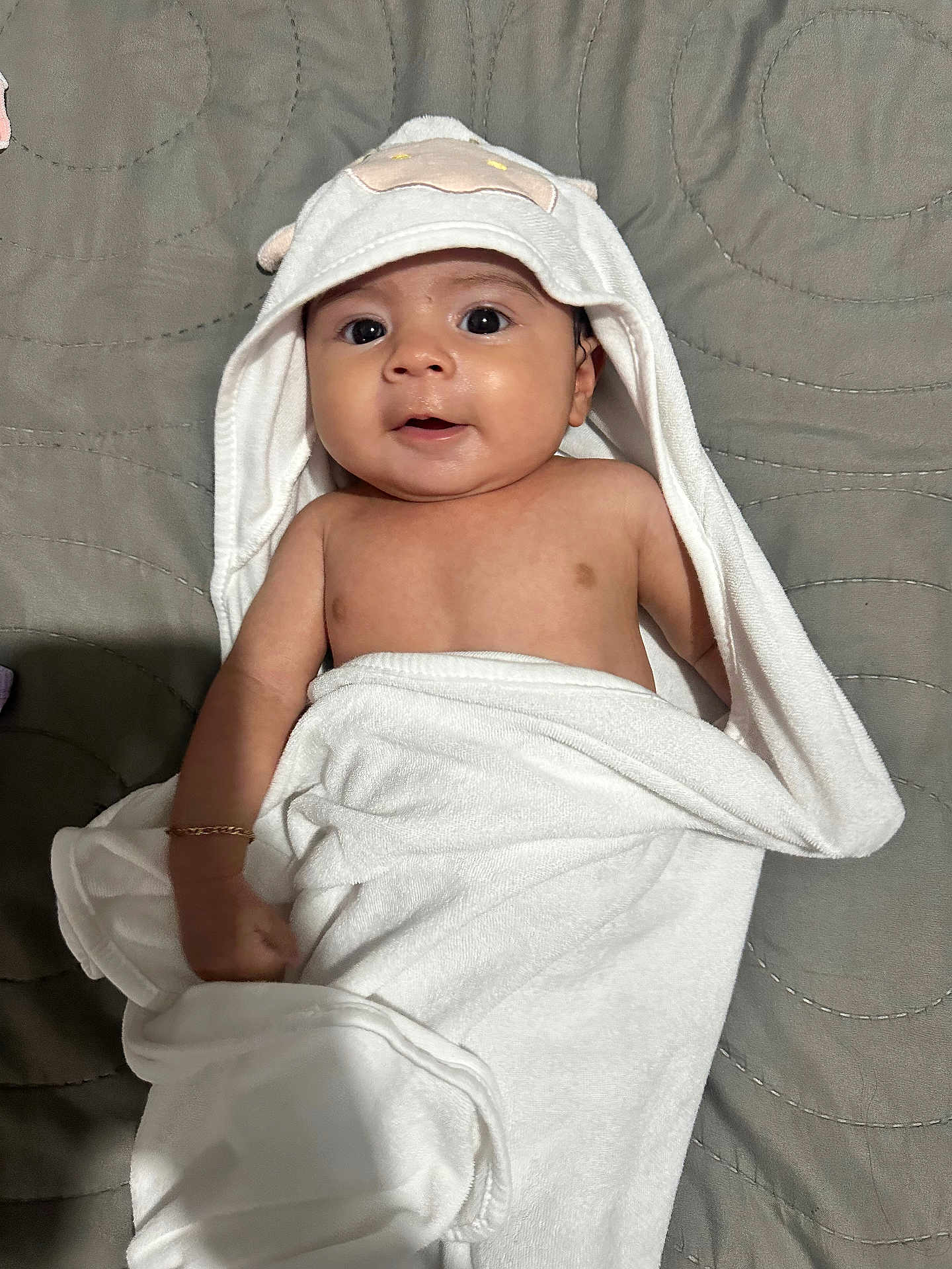 Mia Itzayana is registered to the contest to win money with this photo: baby, infant, towel, hooded_towel, cute, smiling, face, skin, arm, blanket, lying_down, indoors, child, person, fabric, soft, comfort, warm, expression, bed