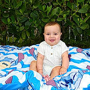 Thiago joined the competition — help win amazing prizes! baby, child, smiling, blanket, outdoor, greenery, leaf, nature, cute, happy, sitting, infant, portrait, clothing, shorts, shirt, skin, foot, face, person