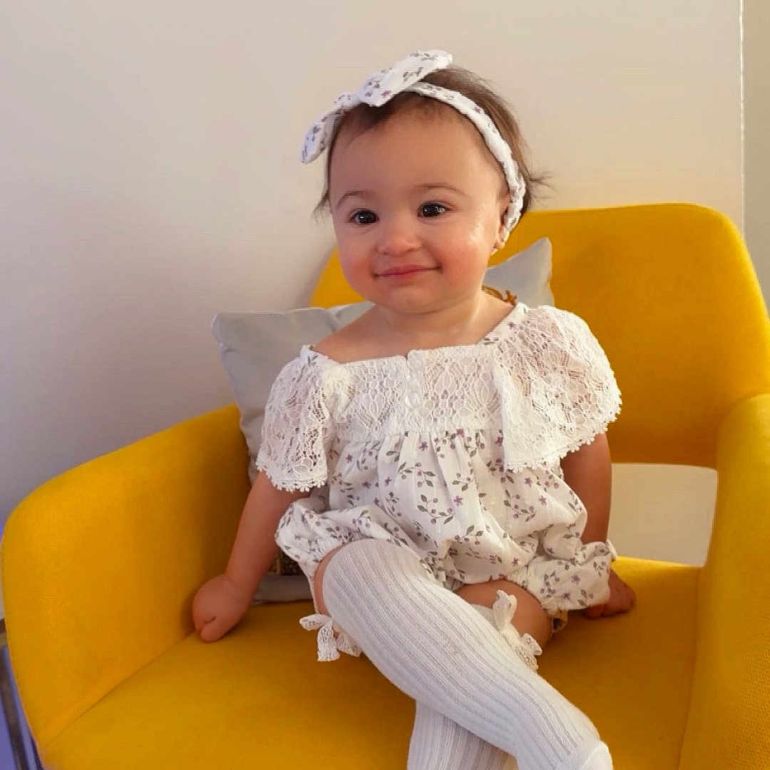 Misk is registered to the contest to win money with this photo: baby, carpet, casual, child, cute, elegant, fashion, furniture, happy, headband, home, indoor, knee_high_socks, portrait, seated, smile, toddler, white_dress, yellow_chair, young_child