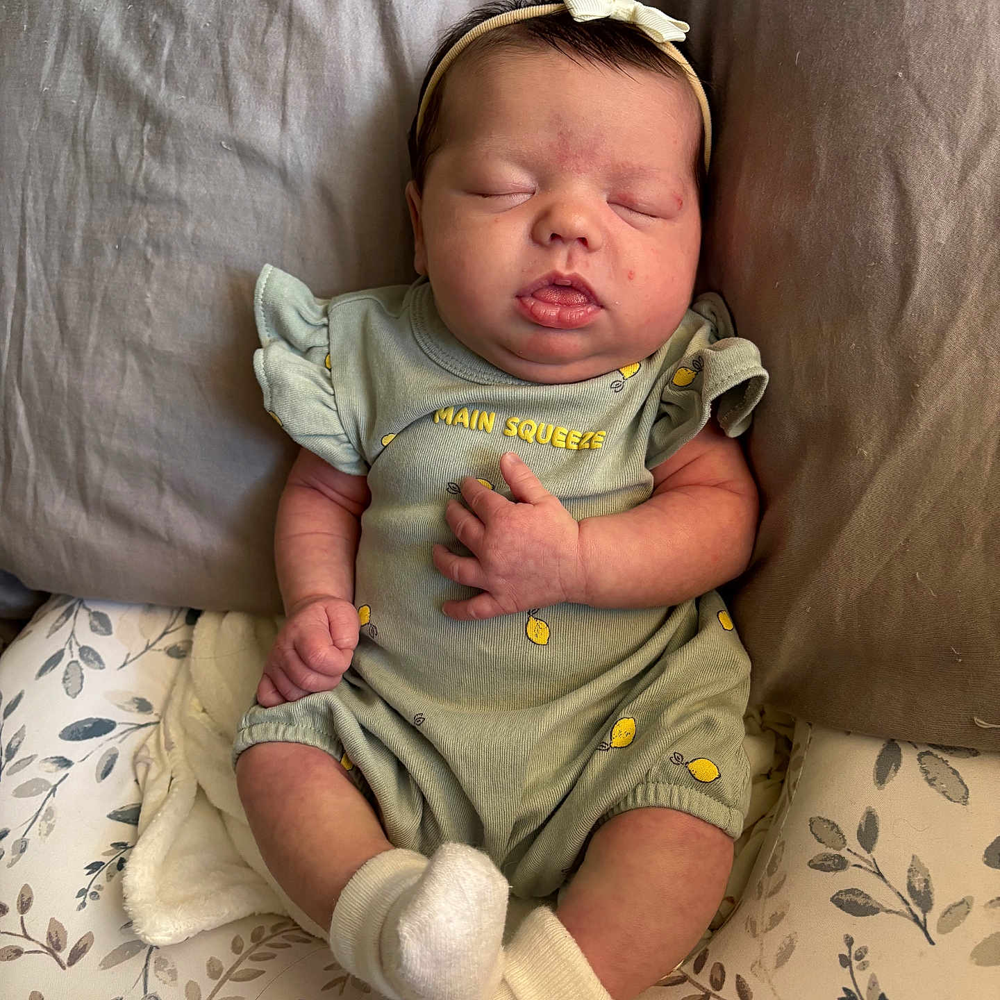 Lillian joined the competition — help win amazing prizes! baby, infant, sleeping, onesie, headband, sock, cushion, blanket, pattern, fabric, hand, face, person, newborn, cute, peaceful, resting, indoors, soft, cozy