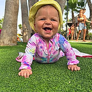 Millie joined the competition — help win amazing prizes! baby, child, smiling, crawling, grass, outdoor, sunhat, tie_dye_clothing, palm_trees, people, summer, vacation, happy, nature, family, playful, sunny, blue_sky, greenery, daytime