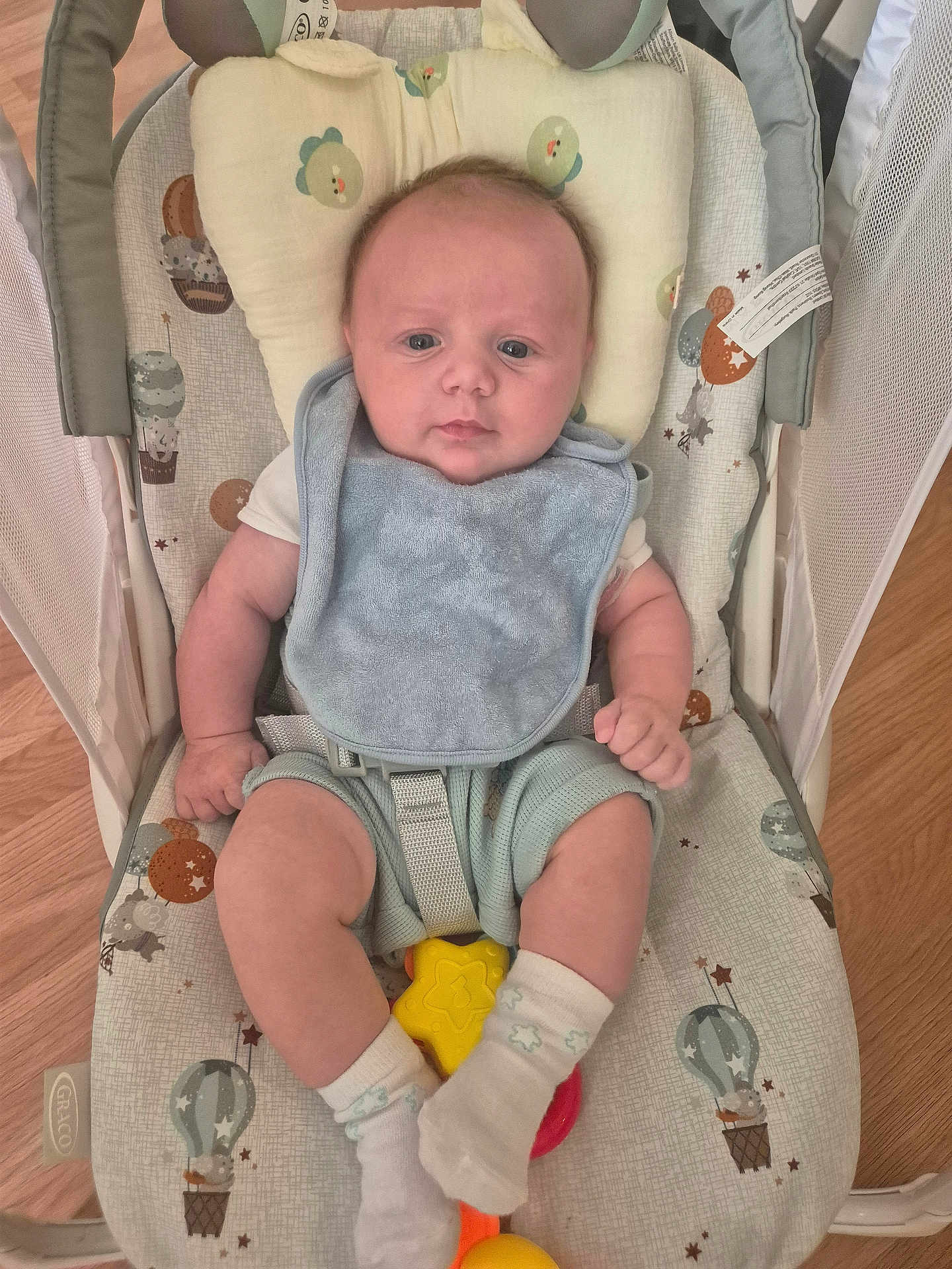 Henley joined the competition — help win amazing prizes! baby, infant, bib, socks, baby_rocker, toy, floor, wooden_floor, headrest, bunny_ears, hot_air_balloon, pattern, cushion, clothing, person, indoor, seated, face, baby_toy, calm