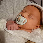 Henley is registered to the contest to win money with this photo: baby, pacifier, sleeping, towel, hand, person, infant, cute, cartoon, white, soft, cozy, skin, clothing, peaceful, closeup, indoors, portrait, newborn, resting